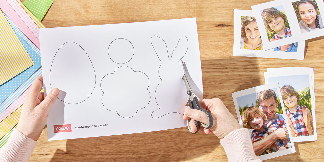 Dve roki sta iz šablone izrezali velikonočne zajčke. Desno od njega so natisnjeni posnetki družine, levo pa različni listi plastelina.